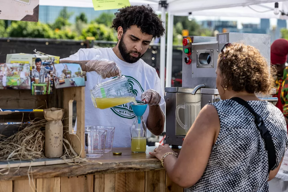 Vendor at Carnival selling juice to customer.